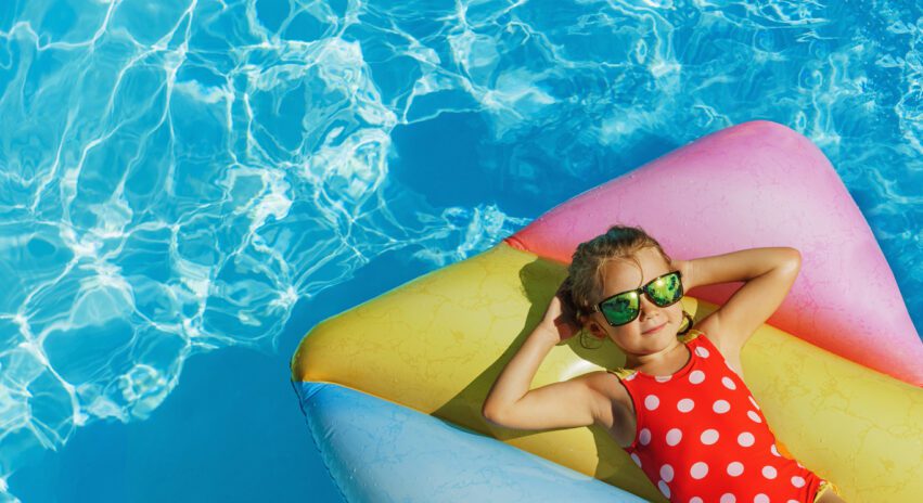 Child in swimming pool. Having fun on vacation at the hotel pool. Colorful vacation concept.